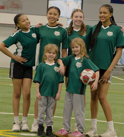 Girls smiling and posing with soccer ball for She Plays Aurora campaign