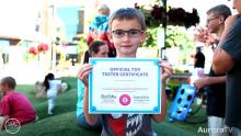 little boy holding up official toy tester certificate