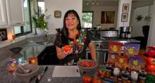 Lindita smiling holding a tomato 