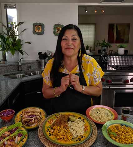 Lindita smiling with Sizzling Fiesta Chicken and side dishes
