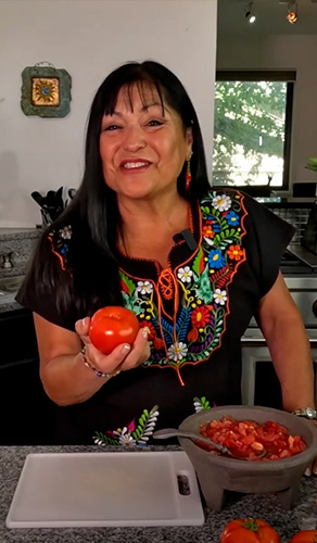 Lindita smiling holding a tomato 