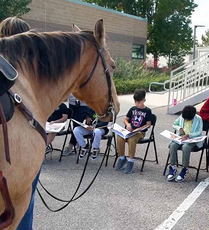 horse watching kids sitting outside and reading