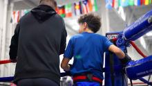 Kid and coach standing outside boxing ring