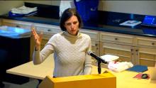 Woman standing at a podium holding up a hand links to the March 25 2024 Aurora City Council Study Session