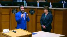 Two people standing in the Aurora City Council Chamber that links to the Council Meeting of April 8 2024