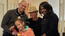 little girl, her mom, dad and another woman posing and smiling