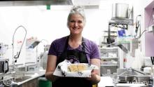 Gina of Gina's Kitchen holding food and smiling