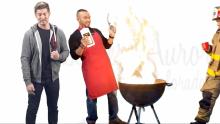 Man with backpack and another man cooking on a grill with flames