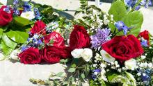Close up of red roses, white carnations, bluish flowers and green leaves