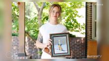 woman wearing white and holding a framed photo of a man snowboarding