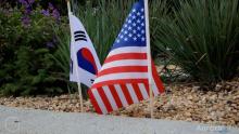 tiny S. Korean and U.S. flag next to pretty purple flowers along sidewalk at war memorial