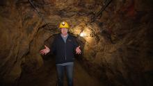 show host walking in mine underground with hard hat on