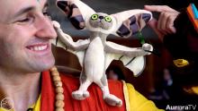 smiling man wearing comic con costume looking at a stuffed critter on his shoulder