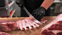 butcher cutting into a rib of meat