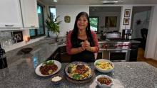 Lindita smiling in her kitchen in front of several plates of Mexican food