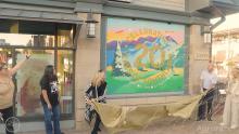 people smiling and laughing as they reveal a colorful mural